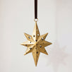 Gold hand-cut iron north star Christmas ornament with a long leading point, hung from a black velvet ribbon