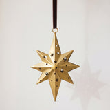 Gold hand-cut iron north star Christmas ornament with a long leading point, hung from a black velvet ribbon