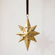 Gold hand-cut iron north star Christmas ornament with a long leading point, hung from a black velvet ribbon