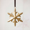 Gold hand-cut iron snowflake Christmas ornament with fine cut detail, hung from a black velvet ribbon