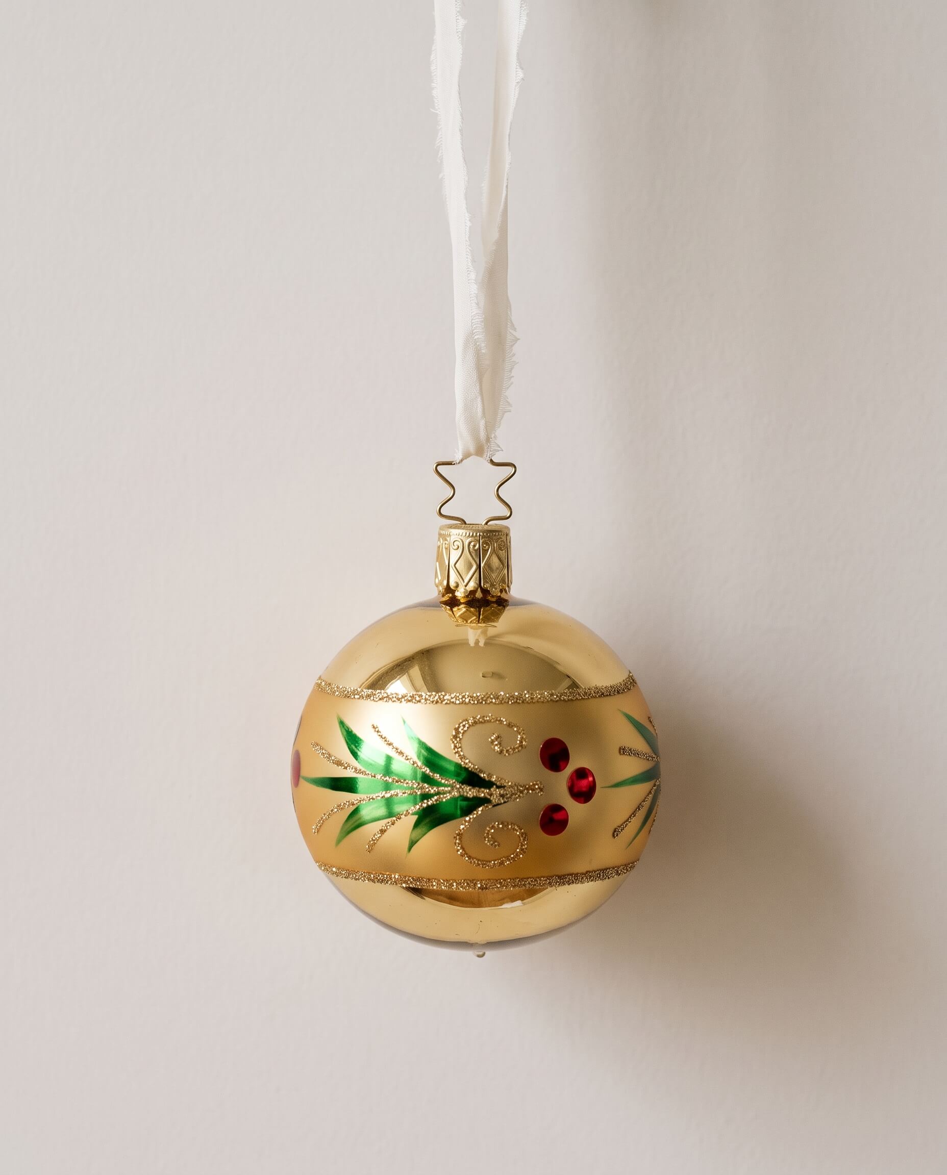 Gold mouth-blown glass ornament with a glittered red and green holly wreath, by Inge-Glas of Lauscha, Germany