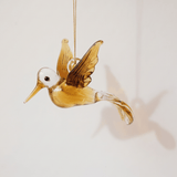 Hand-blown amber glass hummingbird ornament with gold on the wings and tail, made in Old Cairo, Egypt