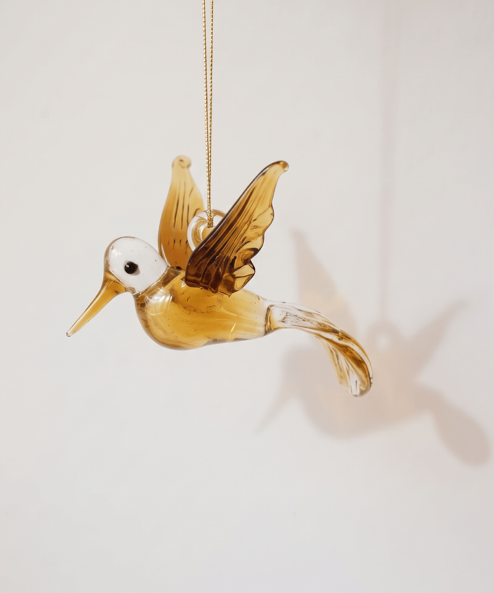 Hand-blown amber glass hummingbird ornament with gold on the wings and tail, made in Old Cairo, Egypt