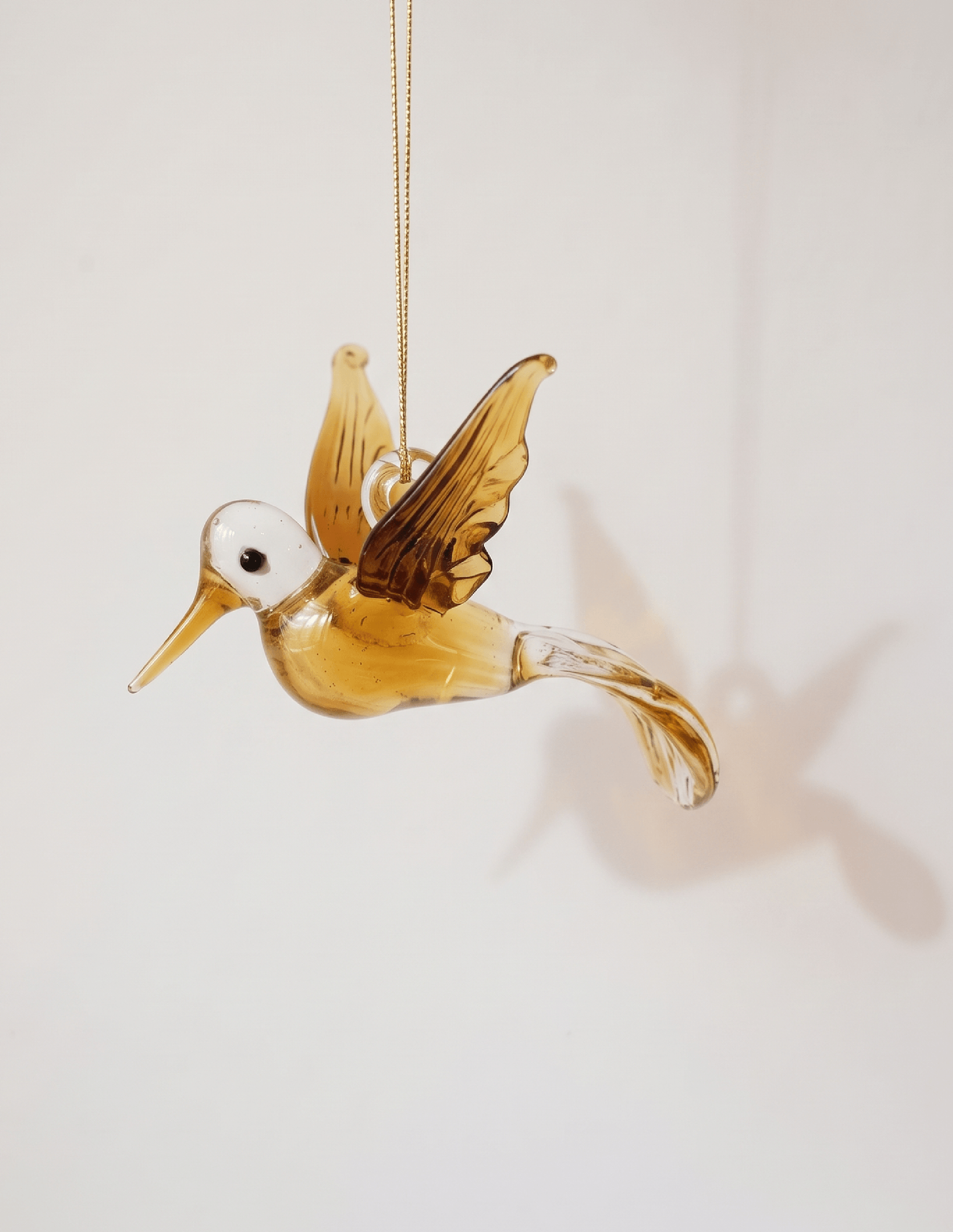 Hand-blown amber glass hummingbird ornament with gold on the wings and tail, made in Old Cairo, Egypt