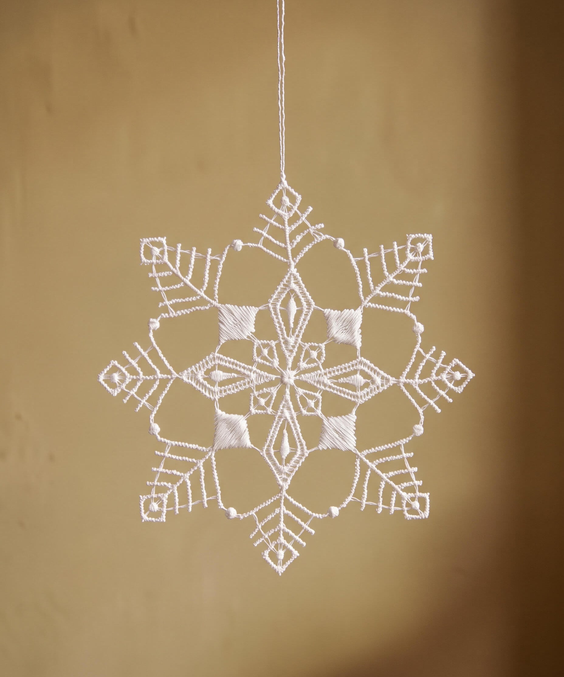 White Plauen lace six-point snowflake ornament with a diamond point design, made in Plauen, Germany