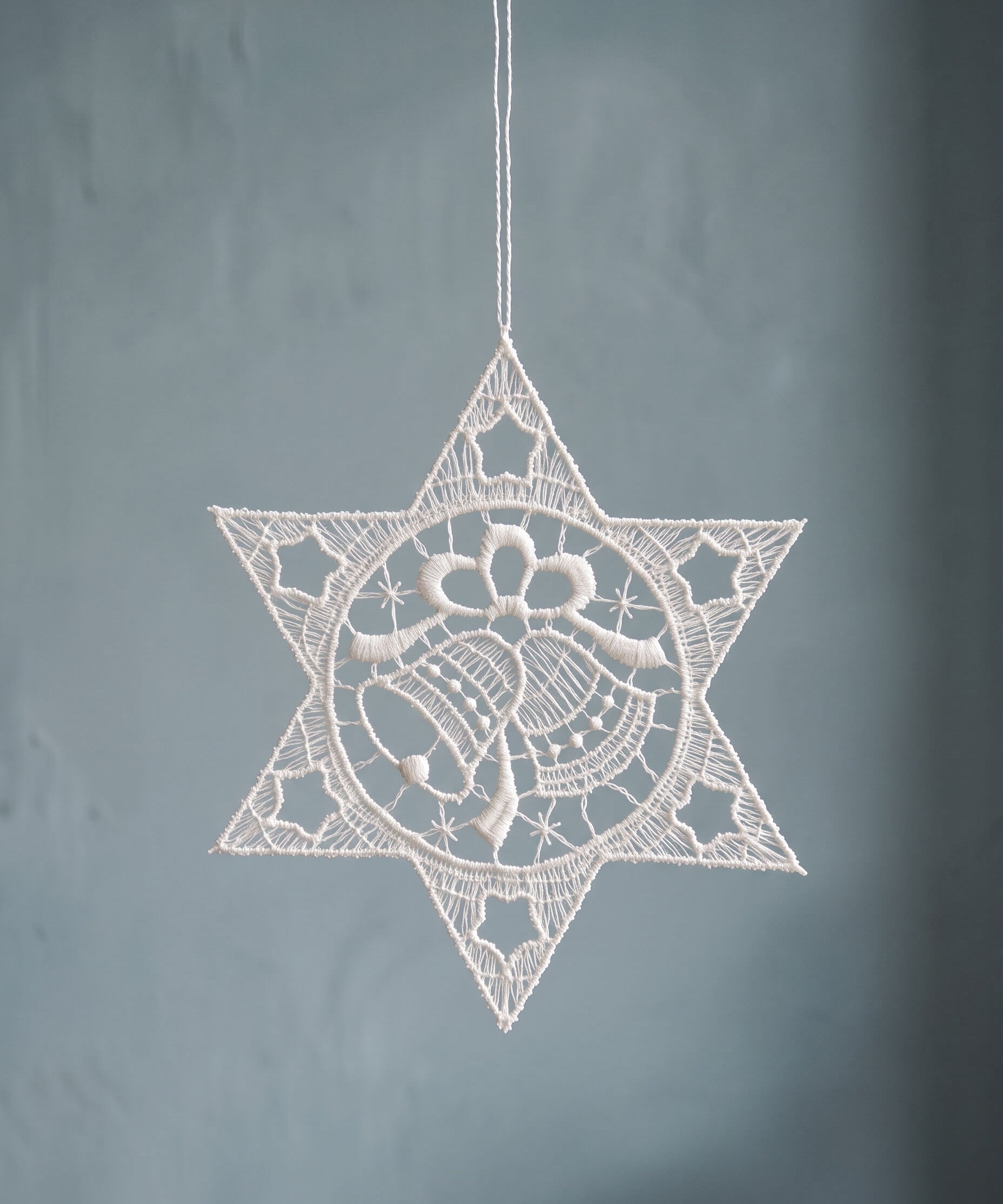 White Plauen lace star ornament with a bell design at the centre, made in Plauen, Germany