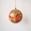 Red papier-mache Christmas ornament hand-painted with a multicoloured floral motif