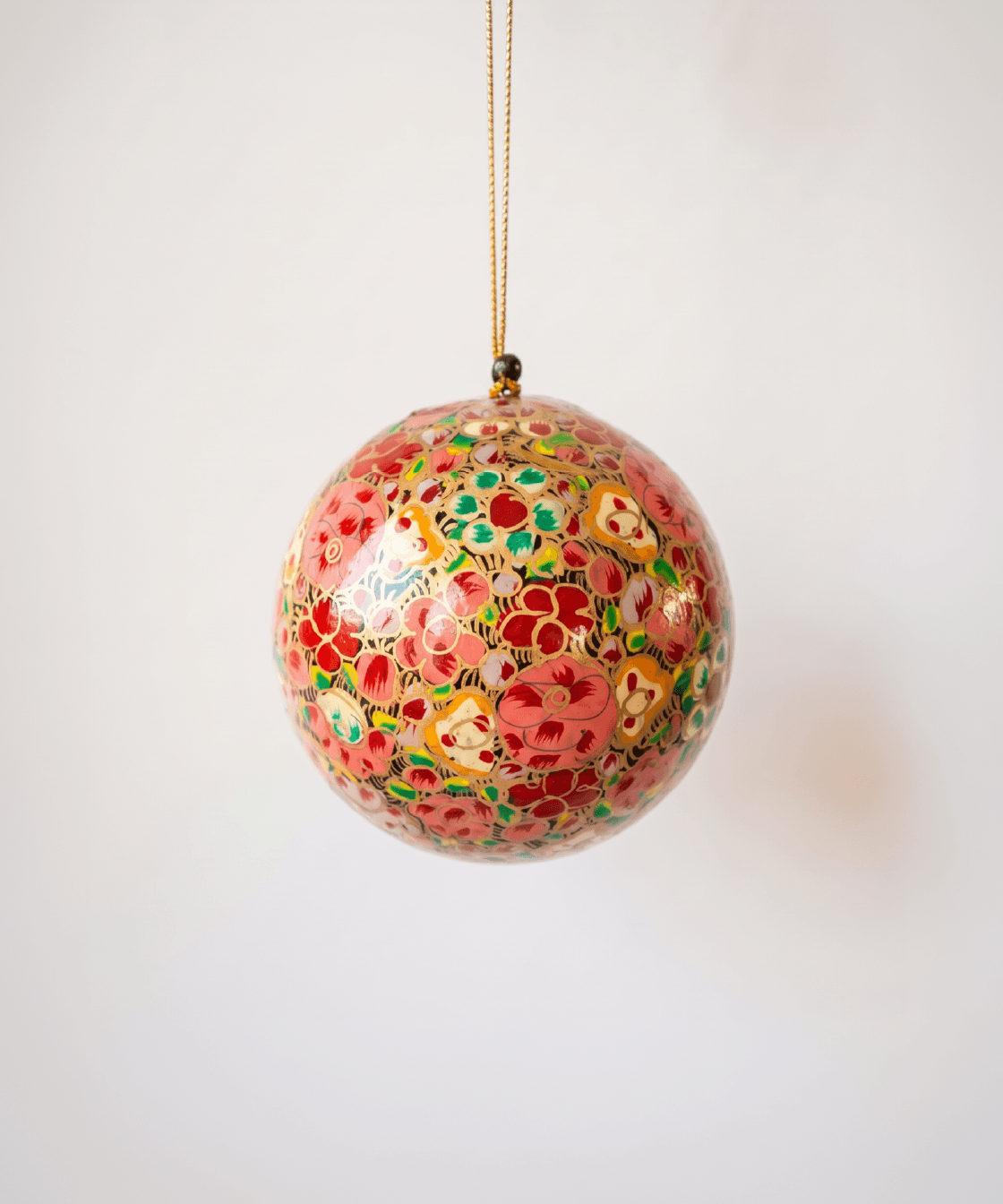 Red papier-mache Christmas ornament hand-painted with a multicoloured floral motif
