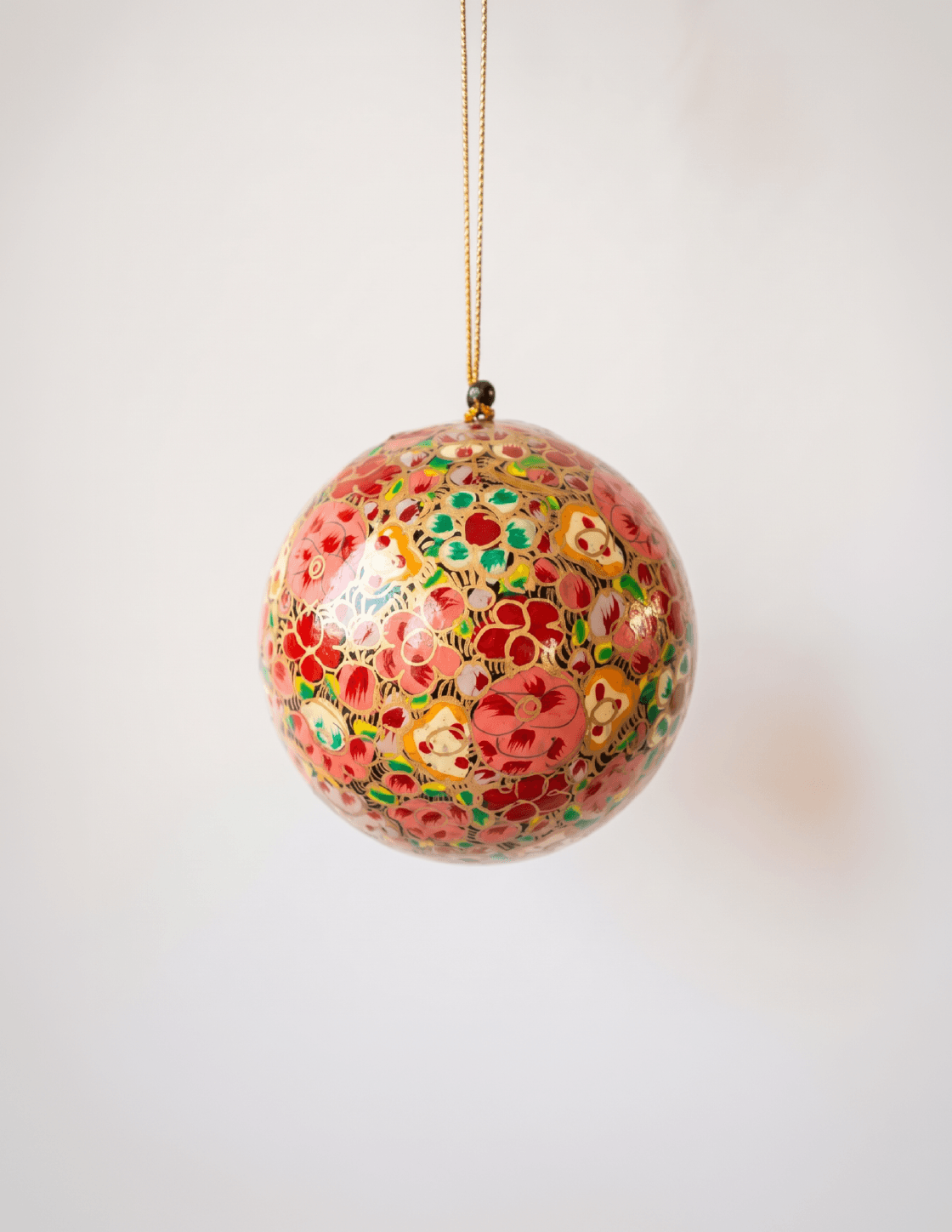Red papier-mache Christmas ornament hand-painted with a multicoloured floral motif