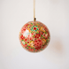 Red papier-mache Christmas ornament hand-painted with a multicoloured floral motif