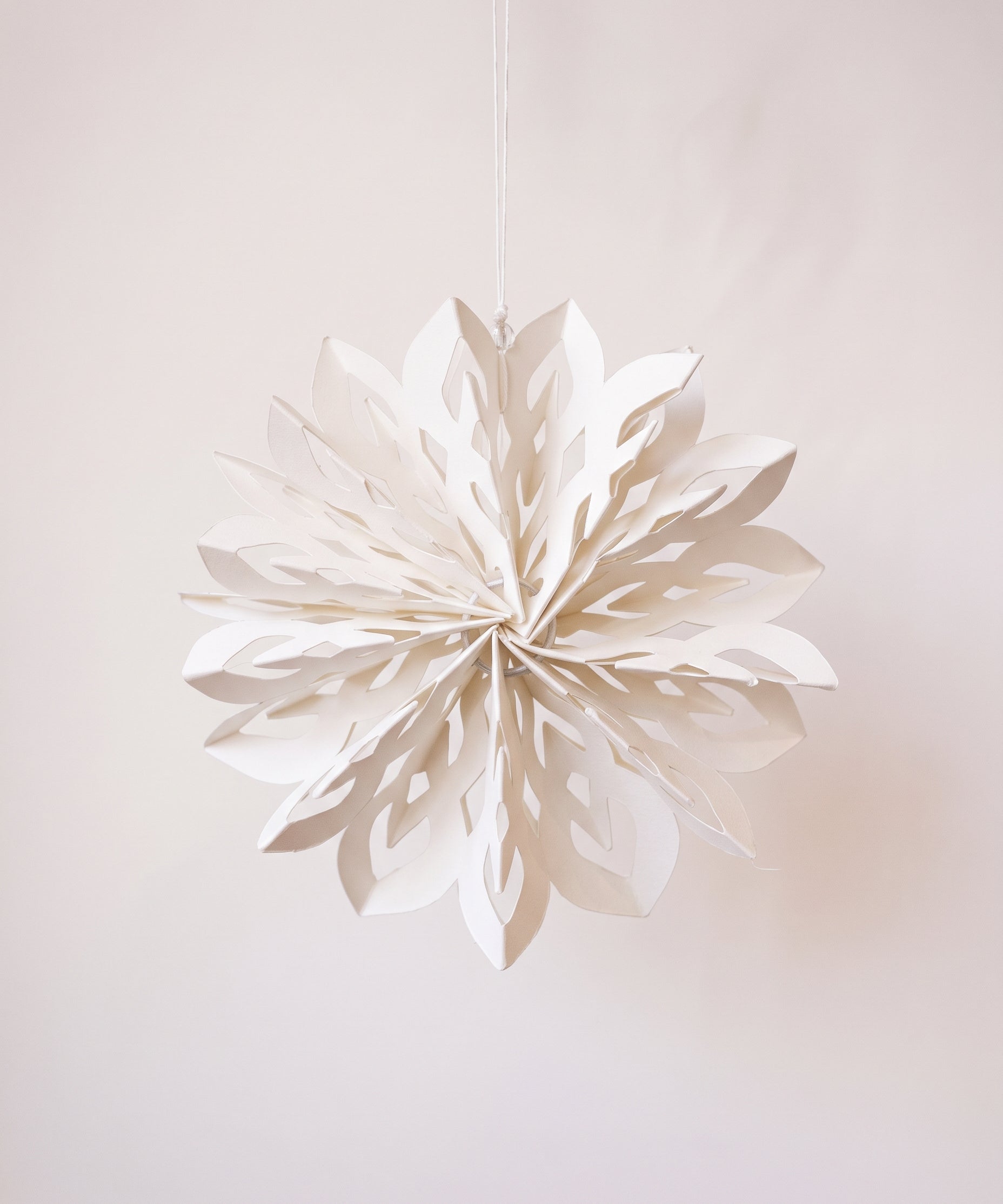 White paper cut snowflake ornament with a cotton hanger, inspired by Scandinavian paper craft
