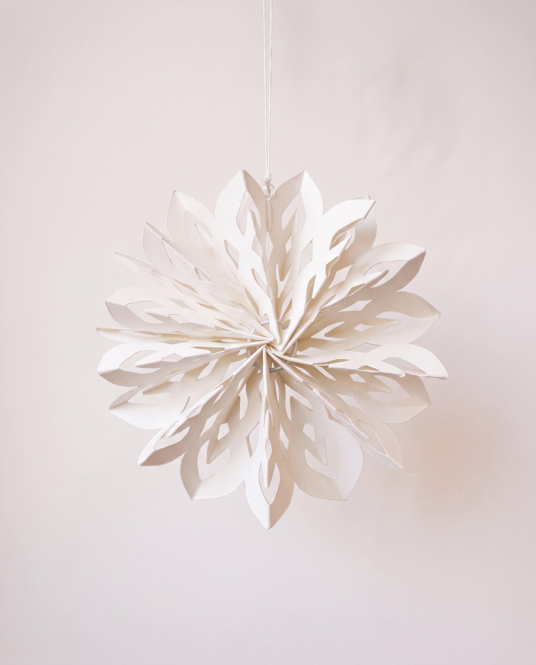 White paper cut snowflake ornament with a cotton hanger, inspired by Scandinavian paper craft