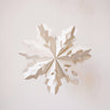 Handmade white paper cut snowflake ornament in a Scandinavian design, with a cotton hanger