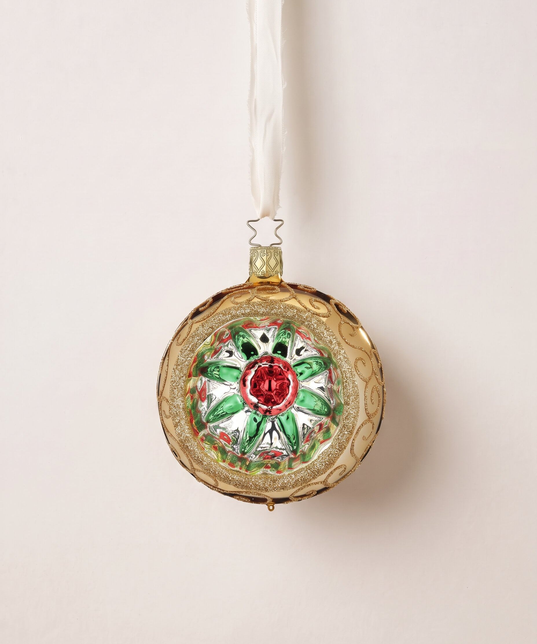 Gold glass reflector ornament with a red and green star centre and gold glitter swirls, by Inge-Glas of Lauscha, Germany