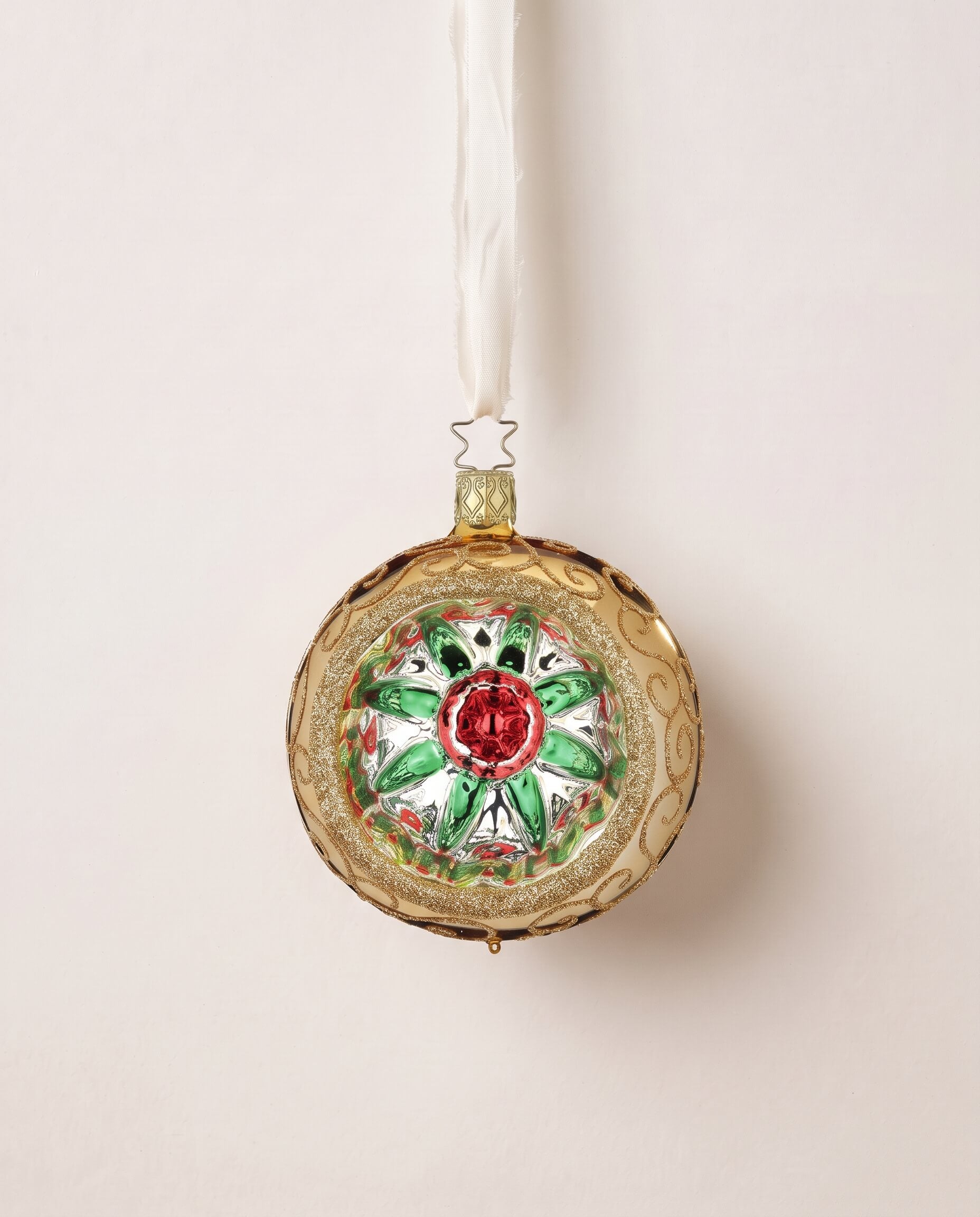 Gold glass reflector ornament with a red and green star centre and gold glitter swirls, by Inge-Glas of Lauscha, Germany